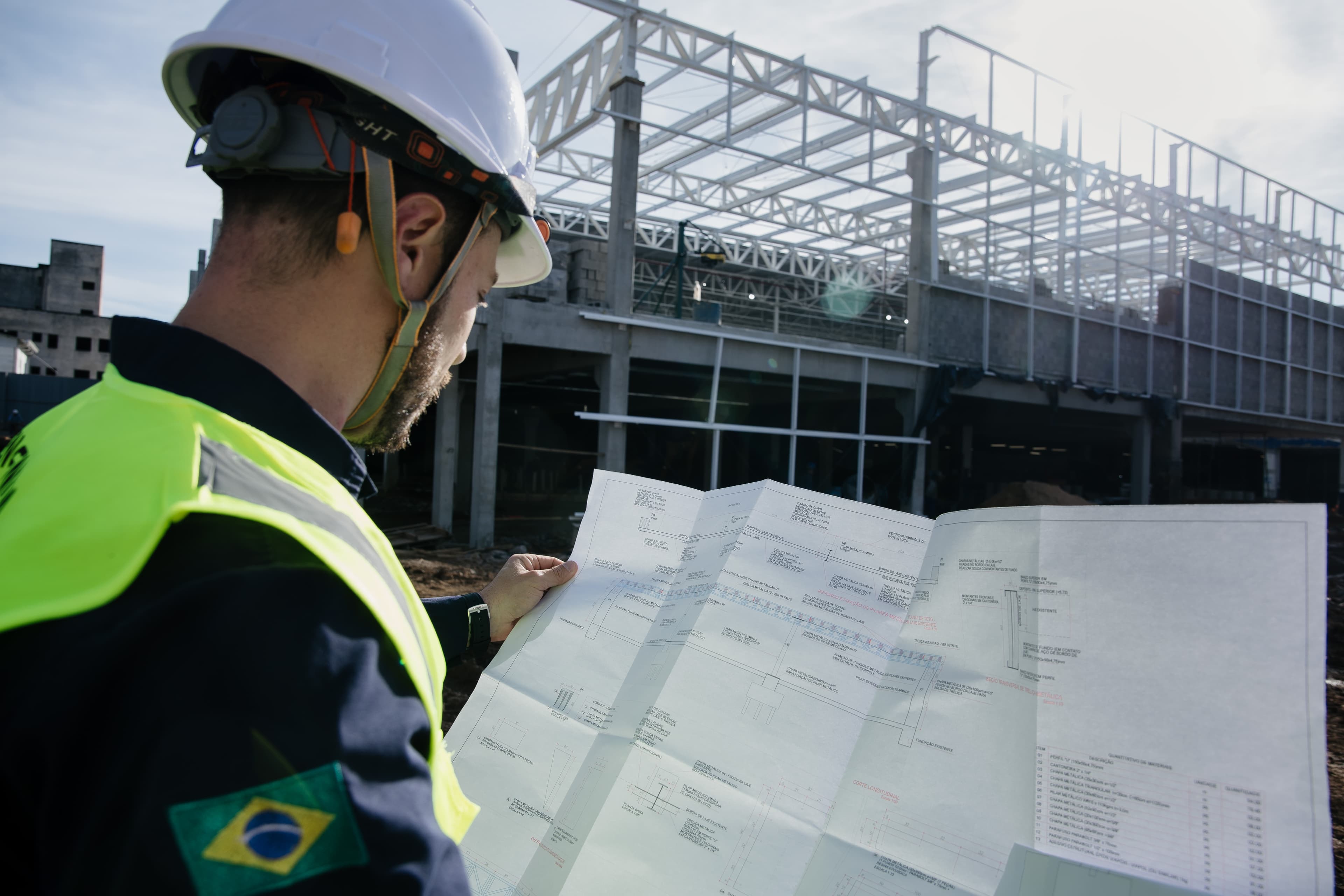 Profissional da ARKON com capacete analisando uma planta no canteiro de obras